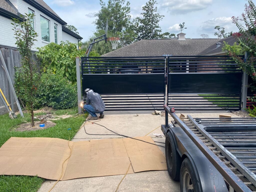 Custom black steel sliding driveway gate being welded during installation by JB Iron & Fences Pro.
