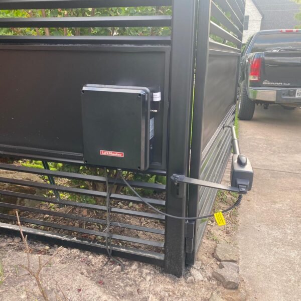 Black steel sliding driveway gate with LiftMaster automatic gate opener installed at a residential property.