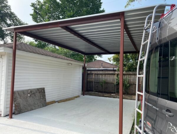 Custom steel carport with metal roof installed over a residential concrete parking area.