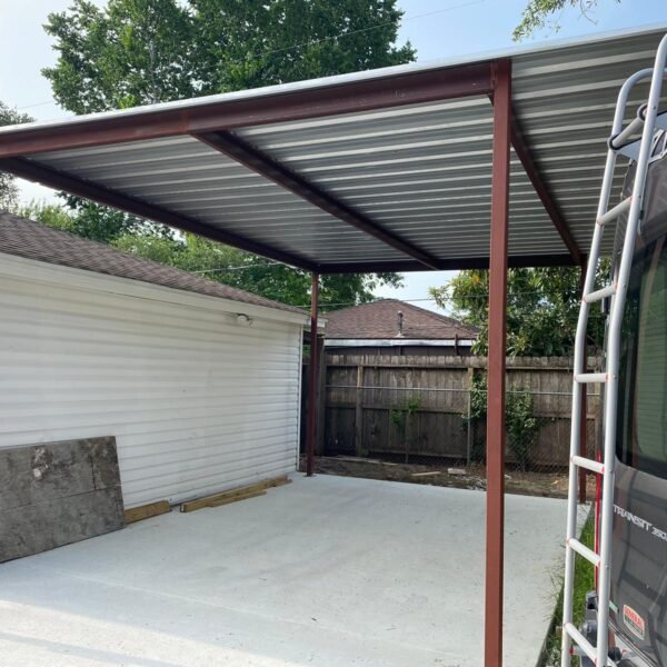Custom steel carport with metal roof installed over a residential concrete parking area.