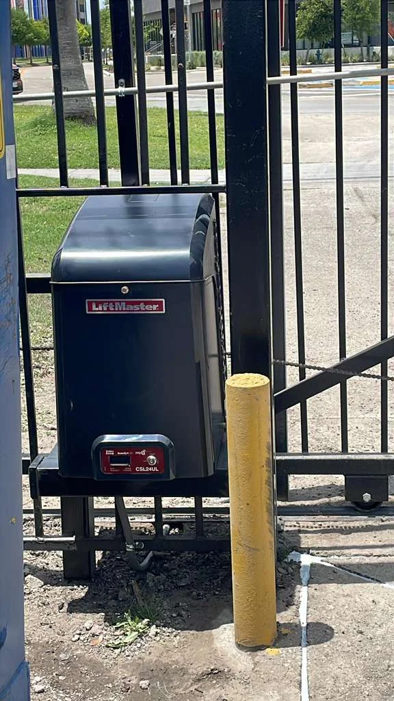 LiftMaster CSL24UL automatic slide gate operator installed on a black iron security fence for a commercial property.